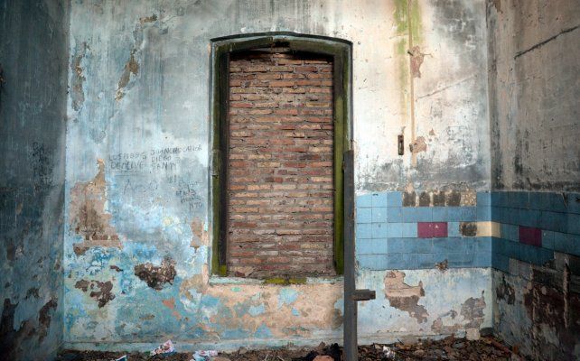 Una de las tantas ventanas tapiadas y unos pocos azulejos de colores en un rinc&oacute;n.