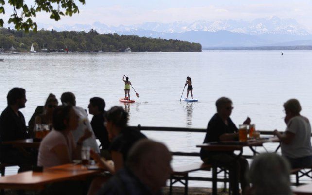 La gente disfruta del clima soleado en el lago Ammersee, frente a los Alpes en Inning, Alemania. La reapertura de las cervecerías al aire libre, tras el levantamiento de las medidas para evitar la propagación del coronavirus movilizaron a la gente a lugares abiertos para disfrutar del buen clima.