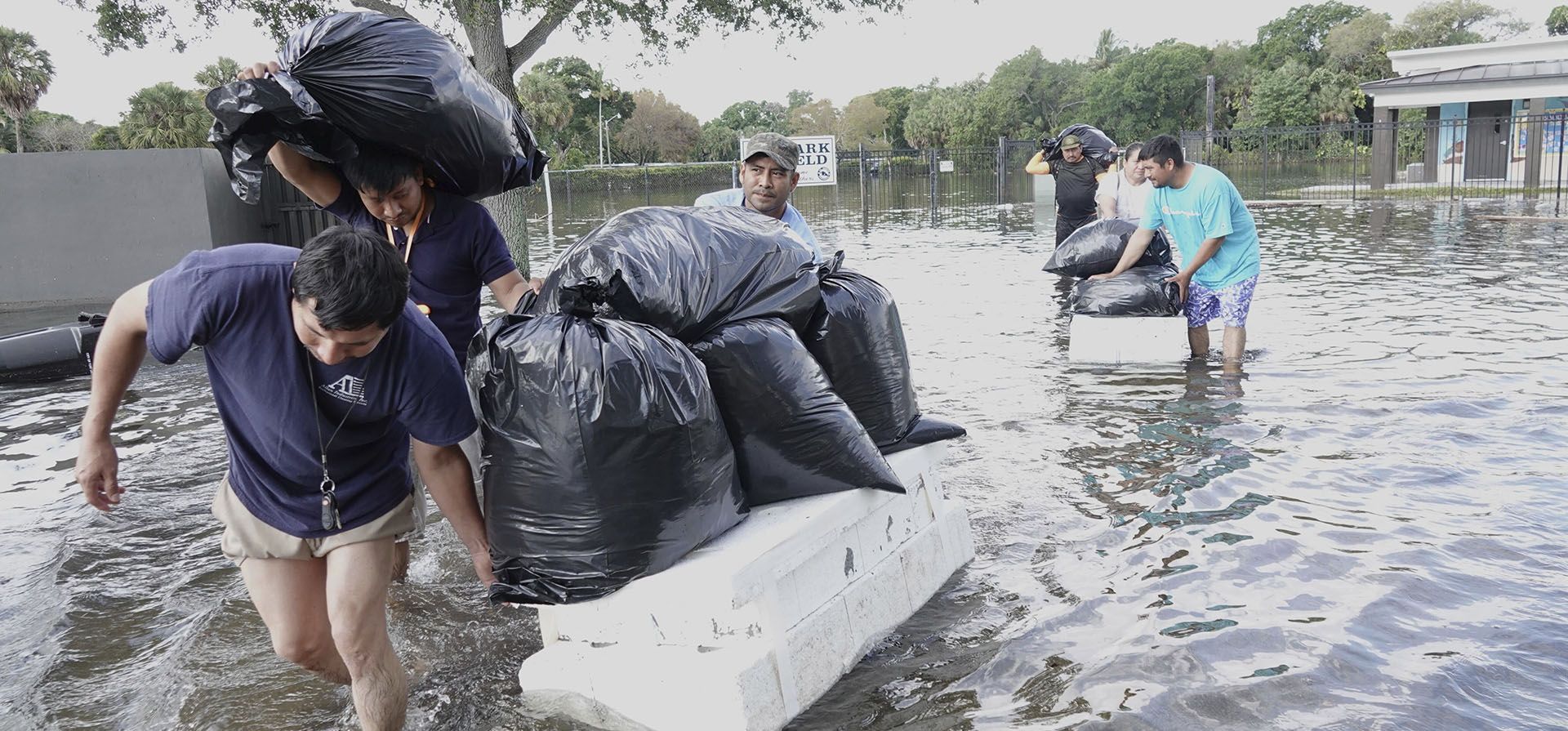 La gente trata de salvar objetos de valor, vadeando a través de las aguas de inundación en un vecindario de Fort Lauderdale, Florida, el jueves 13 de abril de 2023. Las lluvias provocaron inundaciones generalizadas, cerraron el aeropuerto de Fort Lauderdale y convirtieron las carreteras en ríos. (Joe Cavaretta/South Florida Sun-Sentinel vía AP)