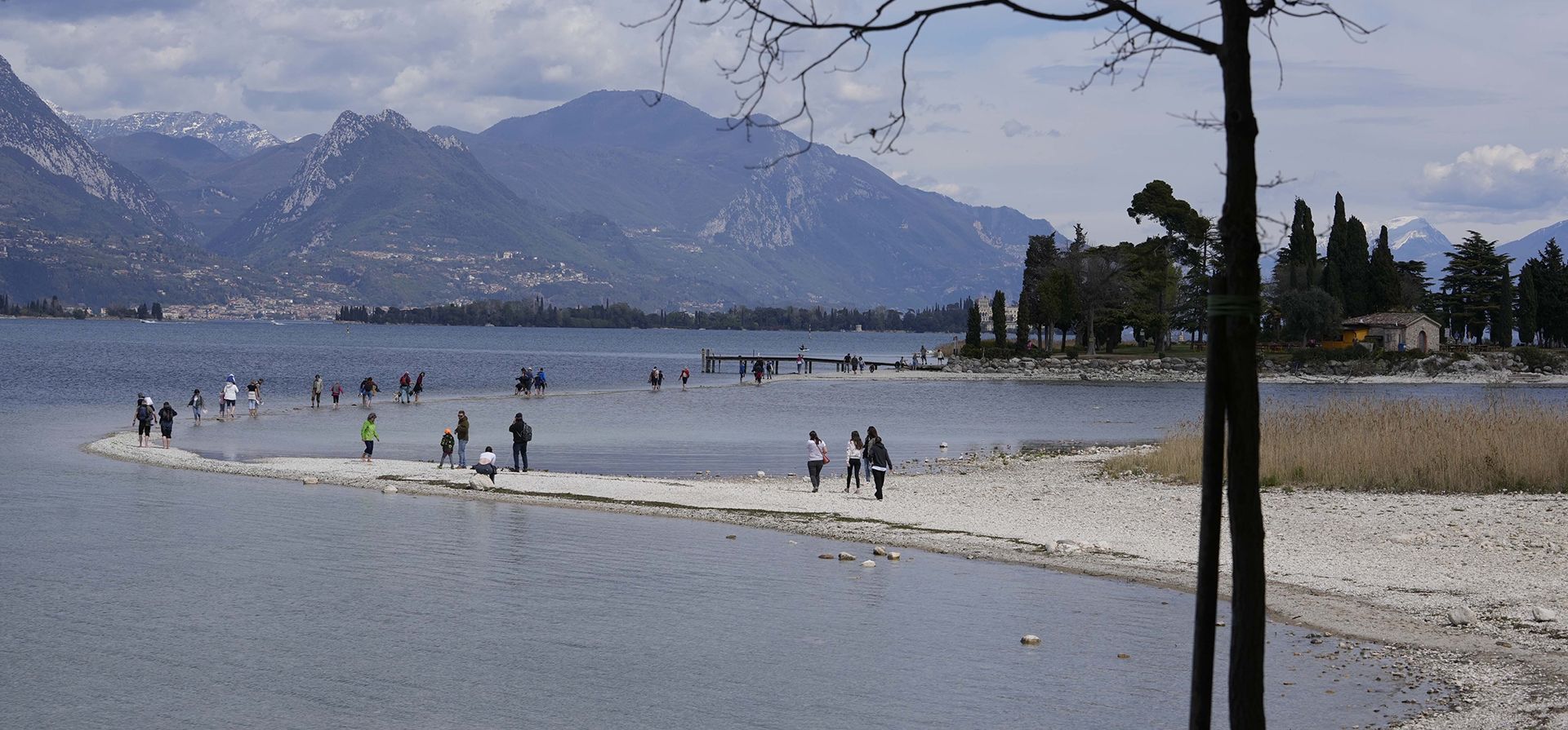 Turistas cruzan un tramo entre el continente y la isla de San Biagio en Manerba, en el lago de Garda, Italia, el viernes 14 de abril de 2023. (Foto AP/Luca Bruno)