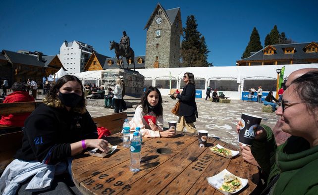 Turistas prueban bocados patagónicos en una mesa montada en el Centro Cívico de Bariloche.