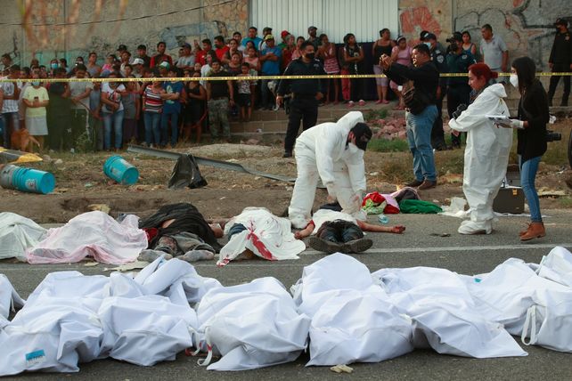 Los cadáveres en bolsas de plástico son dispuestos sobre la carretera.