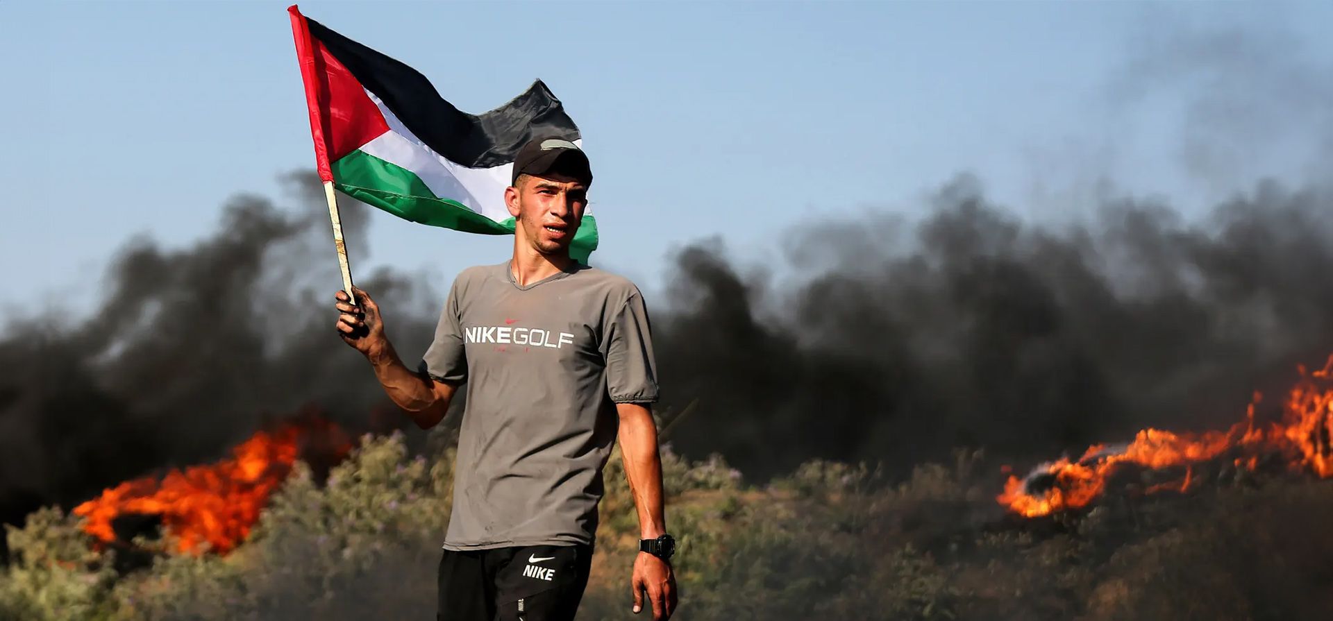 Ciudad de Gaza. Un palestino sostiene una bandera nacional en medio de neumáticos en llamas cerca de la valla fronteriza con Israel, al este de la ciudad de Gaza, durante una protesta contra una incursión militar israelí en Jenin, en Cisjordania. Fotografía: Yousef Masoud/Sopa Images/Shutterstock Ciudad de Gaza. Un palestino sostiene una bandera nacional en medio de neumáticos en llamas cerca de la valla fronteriza con Israel, al este de la ciudad de Gaza, durante una protesta contra una incursión militar israelí en Jenin, en Cisjordania. Fotografía: Yousef Masoud/Sopa Images/Shutterstock