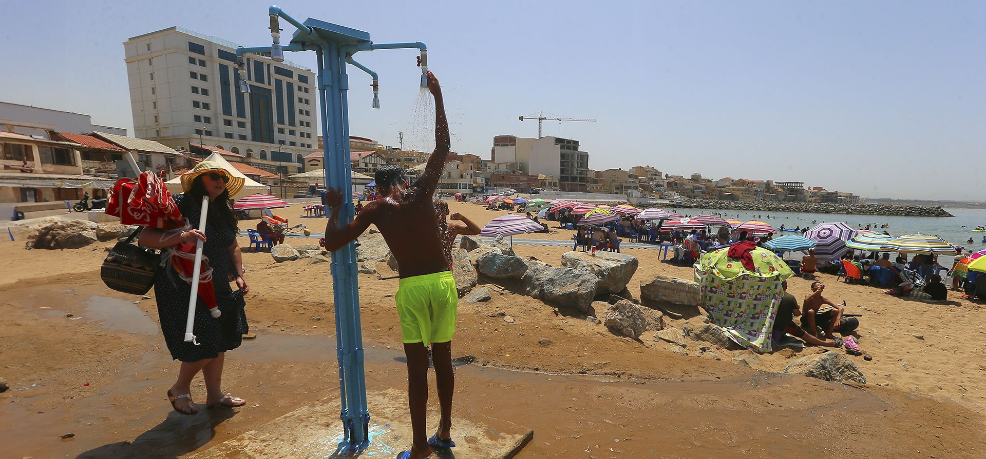 Un niño se ducha en la playa de Madrague, al oeste de Argel, el martes 18 de julio de 2023. Se espera que la temperatura alcance los 43º grados Celsius en la capital argelina. (Foto AP/Anis Belghoul)