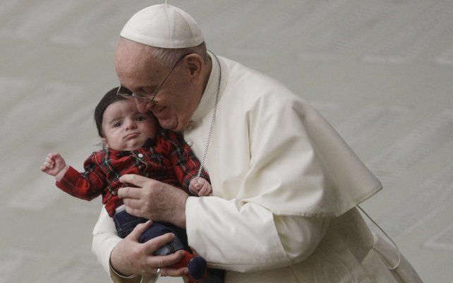 ARCHIVO - El Papa Francisco abraza a un bebé mientras intercambia un saludo navideño con los empleados del Vaticano en el salón Pablo VI. El Vaticano ha confirmado que el Papa Francisco recibió la primera inyección de la vacuna anti-COVID este jueves.