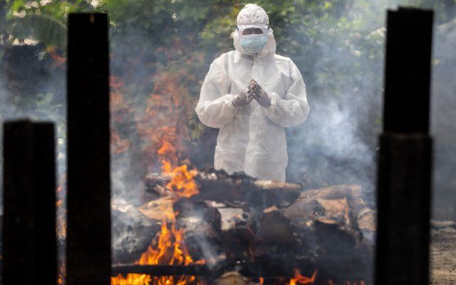 Un allegado a un fallecido realiza los últimos rituales cerca del cuerpo durante la cremación, en Gauhati, India. El país cruzó otro hito sombrío el lunes, más de 300.000 personas fallecidas por el coronavirus por la devastadora oleada de infecciones de COVID-19.
