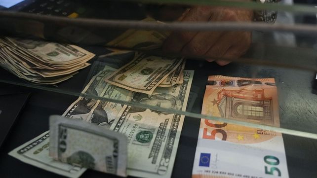 Un cajero cambia un billete de 50 euros por dólares estadounidenses en un mostrador de una agencia en Roma, el miércoles 13 de julio de 2022. El euro cayó el martes a la paridad con el dólar por primera vez en casi 20 años. 