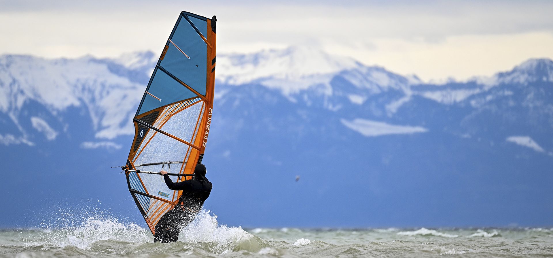 Un hombre surfea las olas del lago de Constanza en su tabla frente a Fischbach en Fischbach, Alemania, el jueves 7 de abril de 2022.
