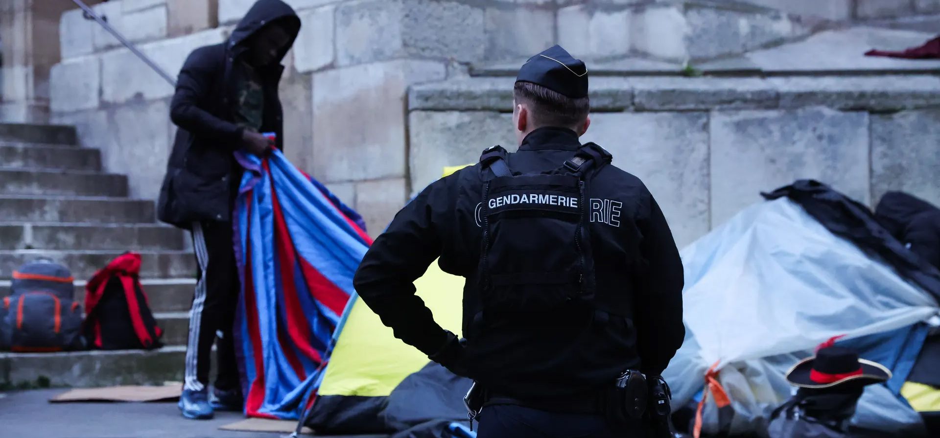 Un gendarme vigila cómo la gente recoge sus pertenencias durante su expulsión de un campo de inmigrantes cerca del ayuntamiento de París, Francia. Fotografía: Teresa Suárez/EPA Un gendarme vigila cómo la gente recoge sus pertenencias durante su expulsión de un campo de inmigrantes cerca del ayuntamiento de París, Francia. Fotografía: Teresa Suárez/EPA