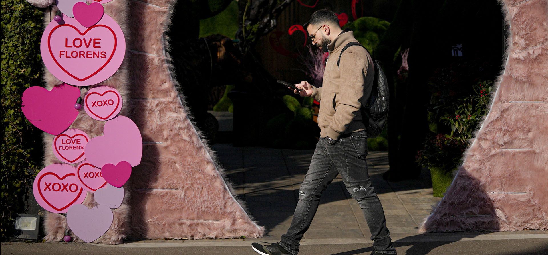 Un hombre camina frente a una floristería decorada con ositos de peluche y recortes en forma de corazón en Bucarest, Rumania, el martes 14 de febrero de 2023. (Foto AP/Andreea Alexandru)