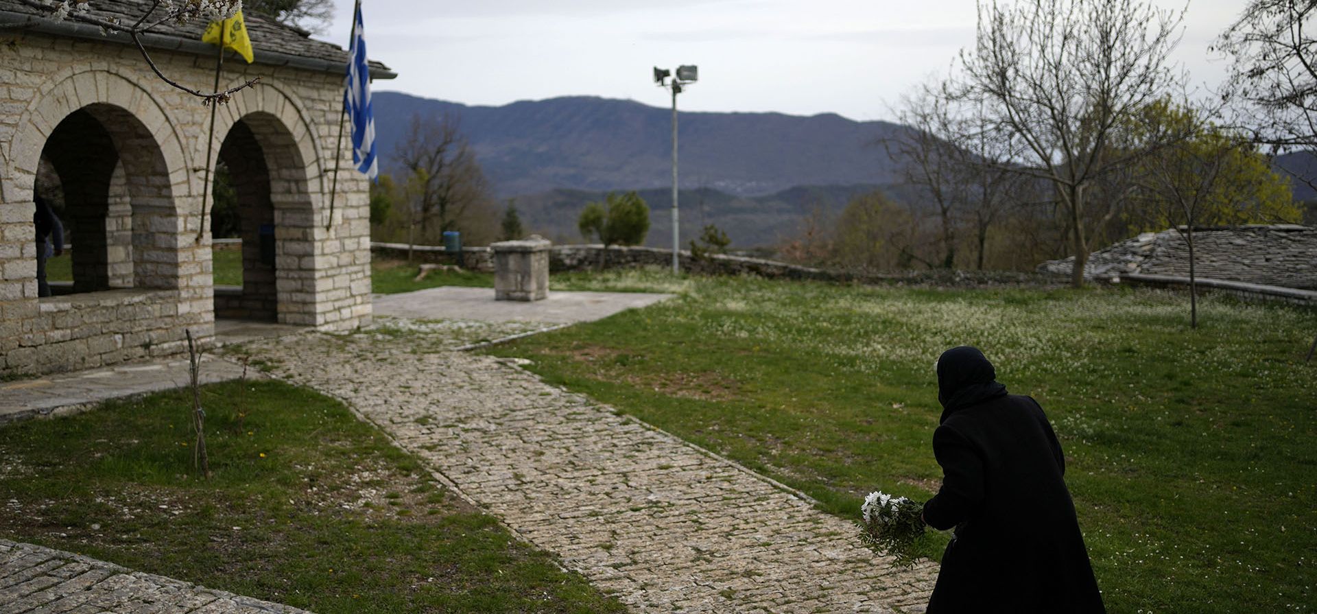 Una anciana sostiene flores al entrar al patio de la iglesia de Agios Georgios en el pueblo de Monodendri Zagorochoria, región de Epiro, noroeste de Grecia. Por primera vez en tres años, los griegos pudieron celebrar la Pascua sin la restricciones necesarias por la pandemia de coronavirus. 