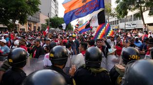 Frente a frente, una columna de manifestantes ante la policía antimotines en una avenida de Lima.