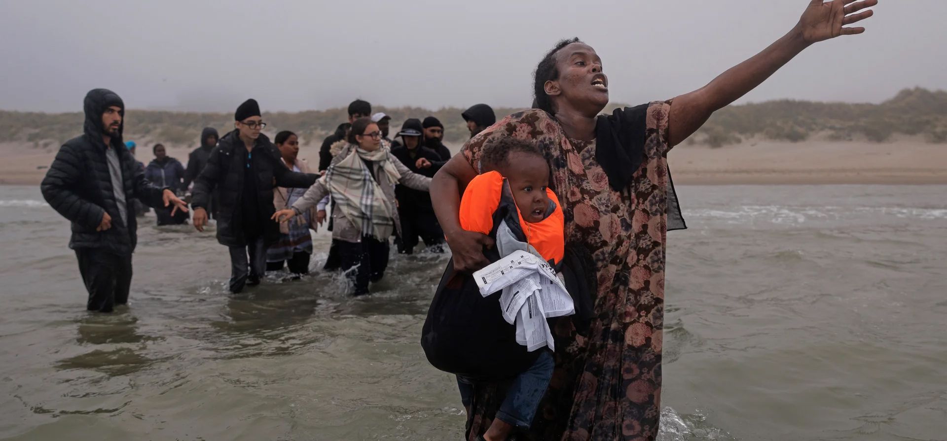 Una mujer con su hijo en brazos ruega a los traficantes que la dejen subir a una pequeña embarcación que llega a la orilla, ya llena de migrantes recogidos de más lejos de la costa, Gravelines, Francia. Fotografía: Dan Kitwood/Getty Images Una mujer con su hijo en brazos ruega a los traficantes que la dejen subir a una pequeña embarcación que llega a la orilla, ya llena de migrantes recogidos de más lejos de la costa, Gravelines, Francia. Fotografía: Dan Kitwood/Getty Images