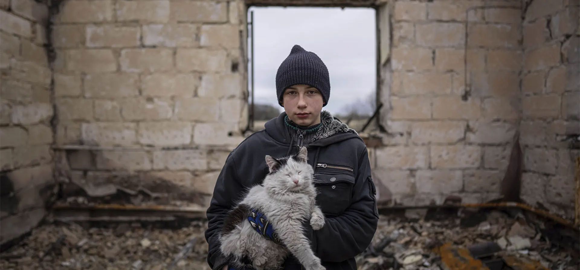 Danyk Rak, de 12 años, sostiene a un gato mientras está de pie sobre los escombros de su casa destruida por los bombardeos de las fuerzas rusas en Chernihiv, Ucrania. Fotografía: Evgeniy Maloletka/AP