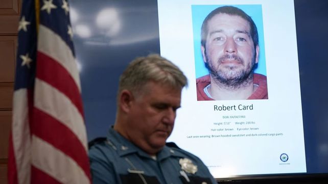 La imagen de Robert Card aparece detrás de un policía del condado de Maine.