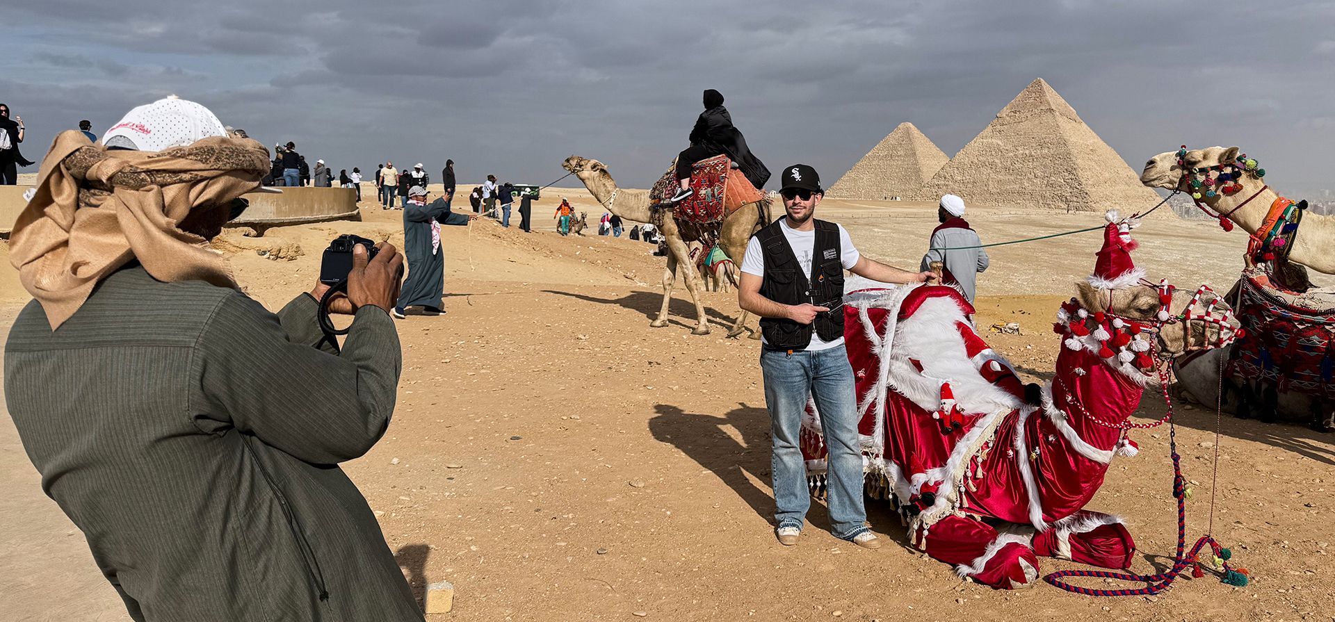 Un guía turístico, toma una foto de un turista con su camello decorado para celebrar la Navidad y el Año Nuevo en el sitio histórico de las Pirámides de Giza, en las afueras de El Cairo, Egipto, el lunes 29 de diciembre de 2025. (Foto AP/Mayar Mokhtar) Un guía turístico, toma una foto de un turista con su camello decorado para celebrar la Navidad y el Año Nuevo en el sitio histórico de las Pirámides de Giza, en las afueras de El Cairo, Egipto, el lunes 29 de diciembre de 2025. (Foto AP/Mayar Mokhtar)
