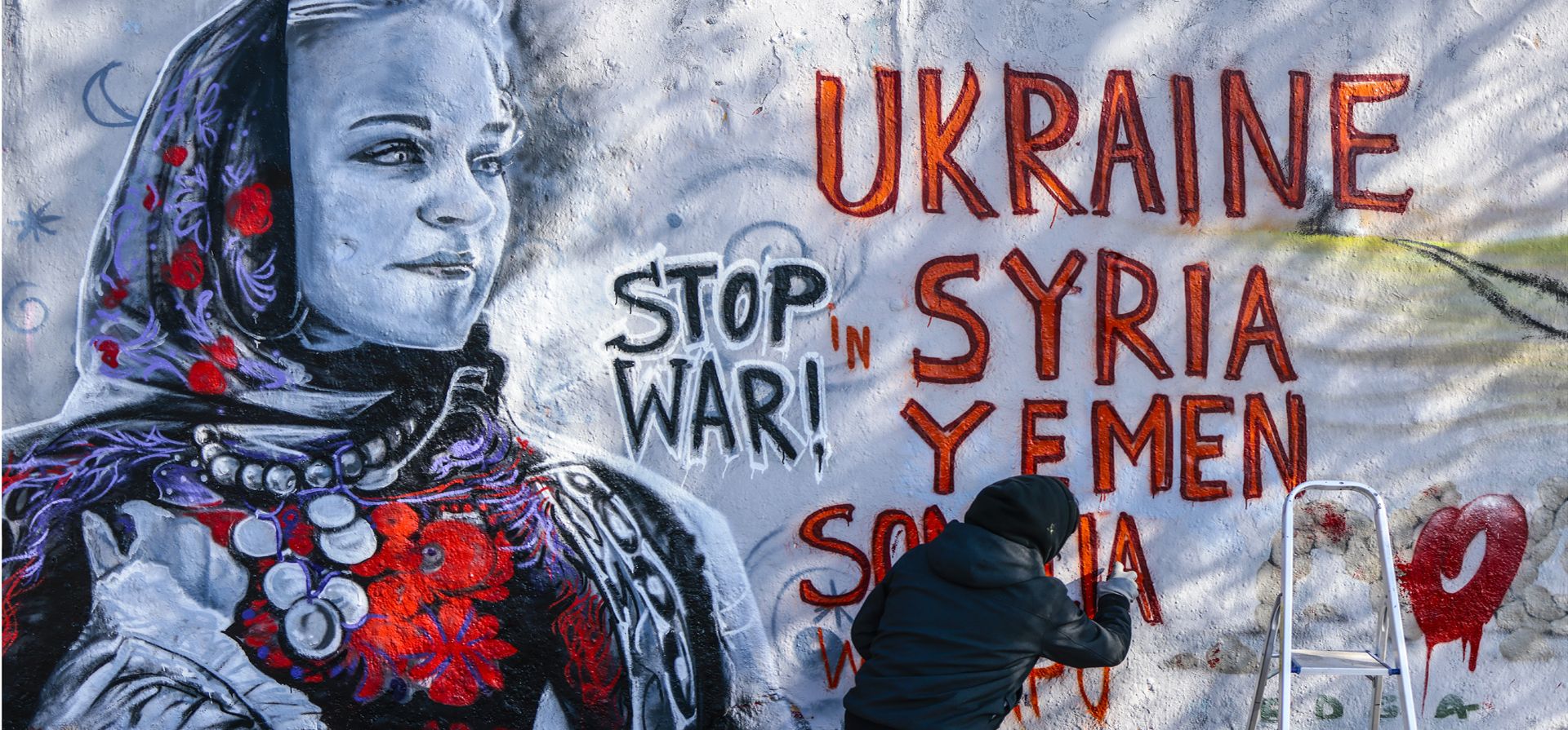 El artista callejero colombiano Arte Vilu, radicado en Berlín, trabaja en un mural que presenta a una mujer ucraniana con vestimenta tradicional en Berlín, Alemania, el lunes 28 de febrero de 2022.