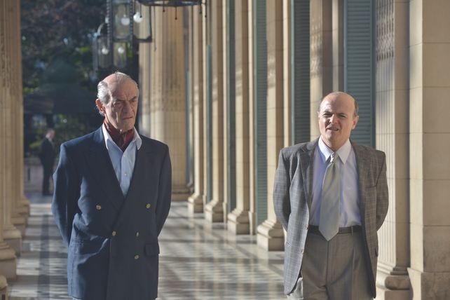 Fernando de la Rúa (por Jean Pierre Noher) camina junto al ministro de Economía, Domingo Cavallo (protagonizado por el rosarino Luis Machín).