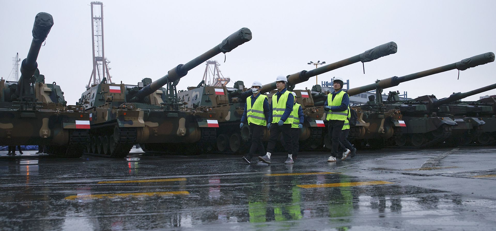 La delegación de Corea del Sur camina junto a los obuses Thunder K9 en el puerto de la Armada polaca de Gdynia, Polonia, el martes 6 de diciembre de 2022. El presidente de Polonia, Andrzej Duda, y el ministro de Defensa dieron la bienvenida el martes a la primera entrega de tanques y obuses de Corea del Sur, elogiando la rápida implementación de un acuerdo firmado en el verano frente a la guerra en la vecina Ucrania. Foto: AP/Michal Dyjuk