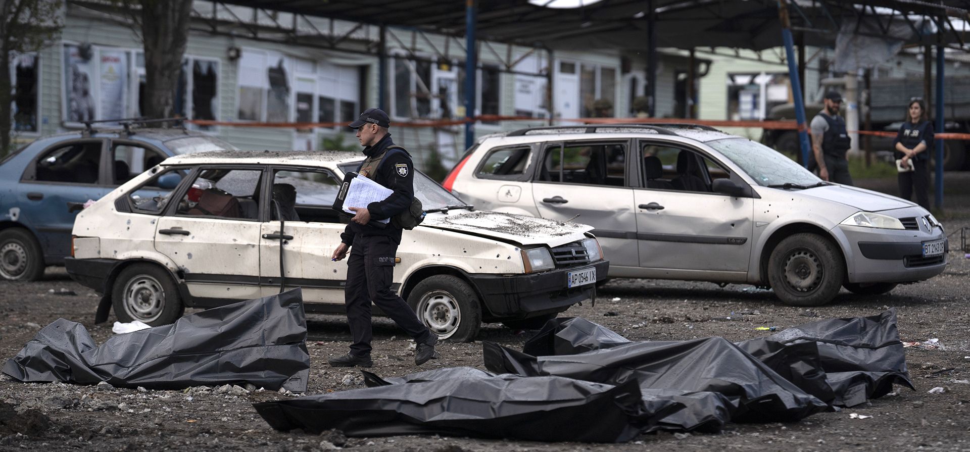 Un oficial de policía ucraniano pasa junto a bolsas que contienen los cuerpos de personas que murieron después de un ataque ruso en Zaporizhzhia, Ucrania, el viernes 30 de septiembre de 2022.