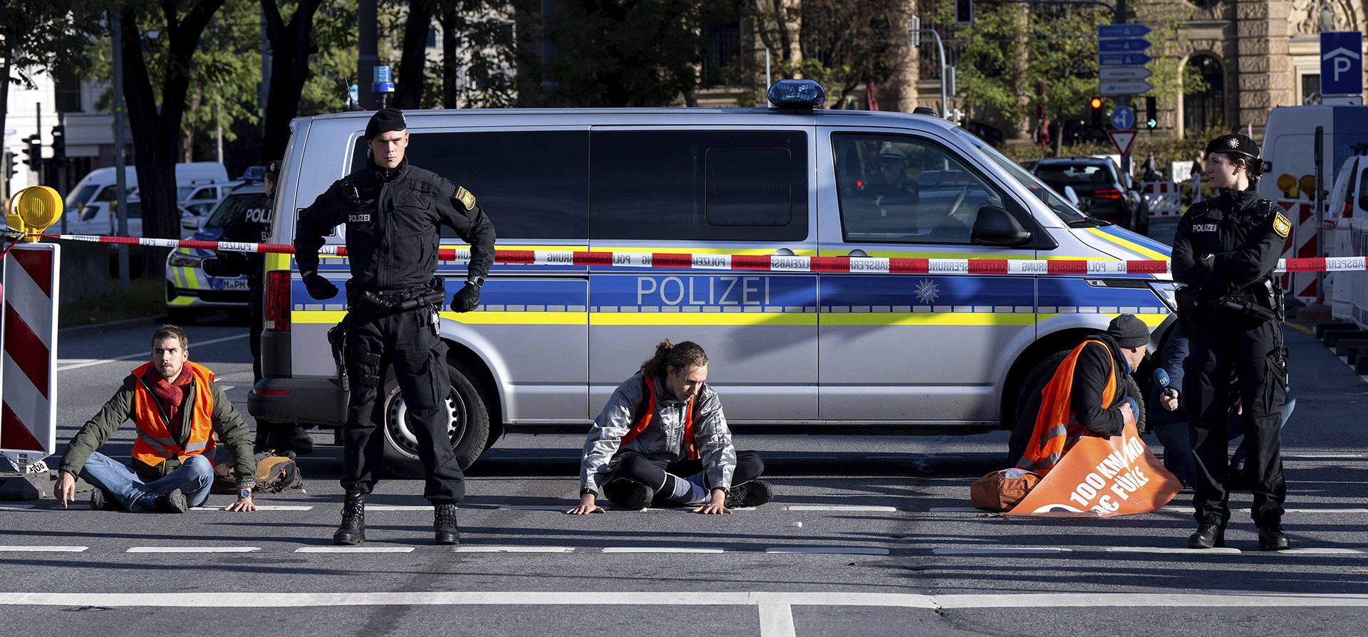 Oficiales de policía junto a activistas climáticos que se pegaron con cinta adhesiva a la carretera en Karlsplatz durante una protesta contra la política climática en Múnich, Alemania, el lunes 7 de noviembre de 2022.