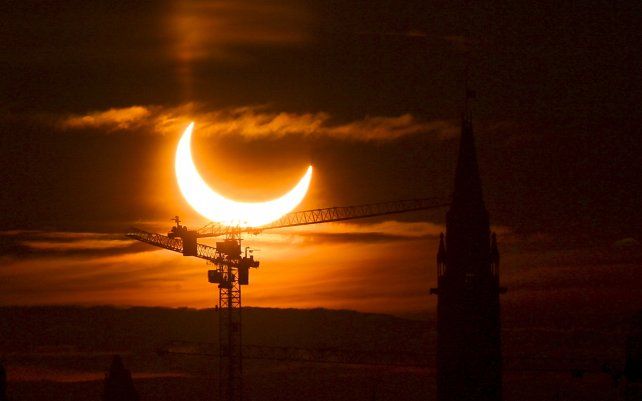 Un eclipse solar anular se eleva sobre las grúas de construcción y la Torre de la Paz en Parliament Hill, Ottawa, Canadá.