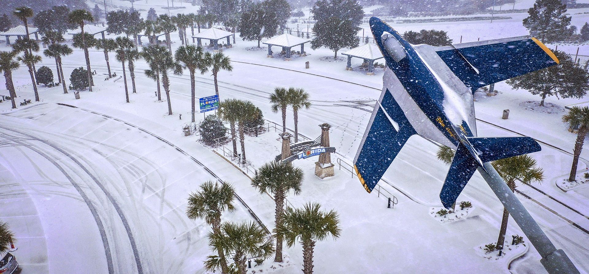 Una fuerte nevada cae sobre las palmeras y el Centro de Bienvenida de Florida el martes 21 de enero de 2025 en Pensacola, Florida. (Luis Santana/Tampa Bay Times vía AP)