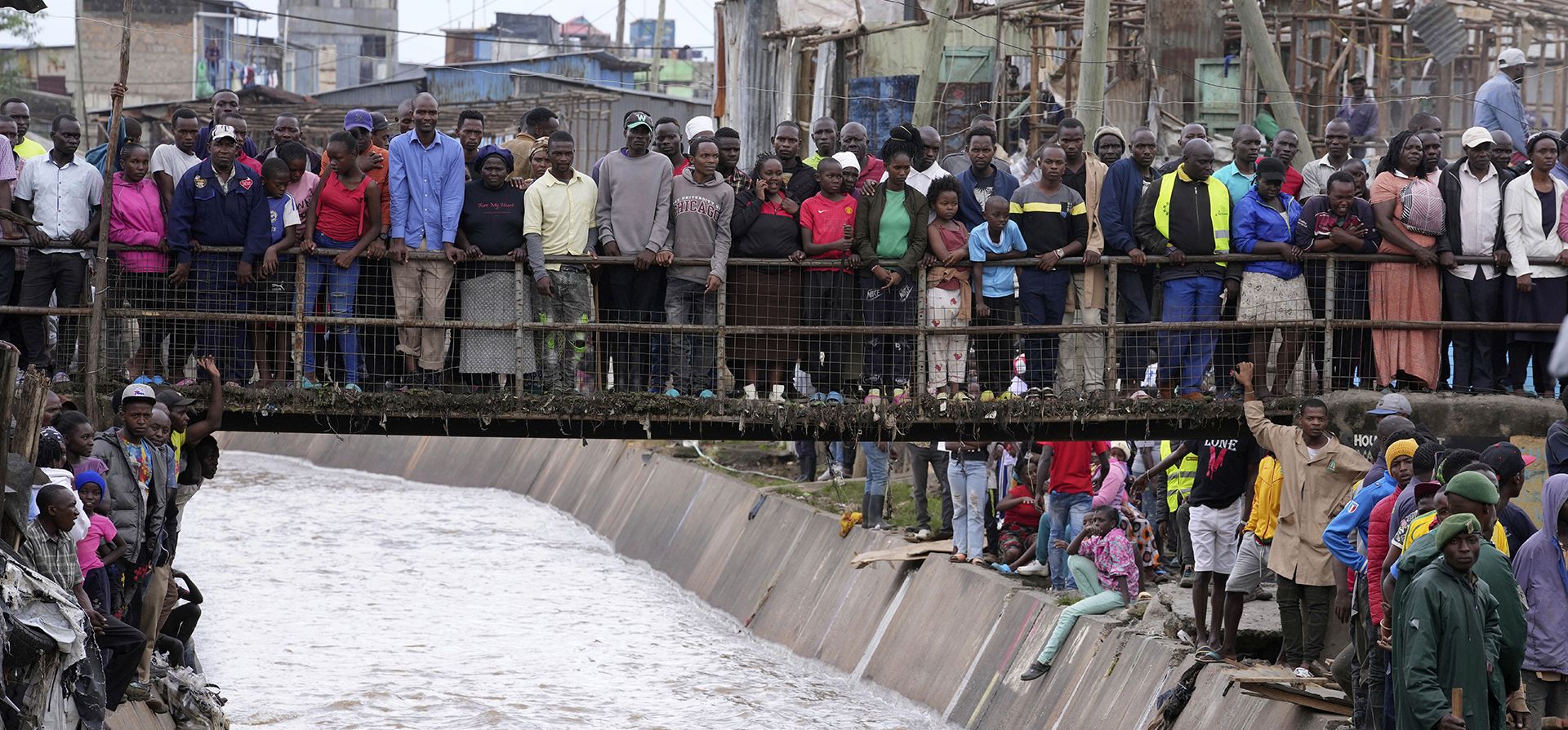 Personas de pie en un puente, observan la demolición de casas en tierras ribereñas en el área de Mukuru en Nairobi. El gobierno ordenó la demolición de estructuras y edificios construidos ilegalmente a lo largo de zonas ribereñas. Kenia, junto con otras partes de África Oriental, se ha visto abrumada por las inundaciones. (Foto AP/Brian Inganga) Personas de pie en un puente, observan la demolición de casas en tierras ribereñas en el área de Mukuru en Nairobi. El gobierno ordenó la demolición de estructuras y edificios construidos ilegalmente a lo largo de zonas ribereñas. Kenia, junto con otras partes de África Oriental, se ha visto abrumada por las inundaciones. (Foto AP/Brian Inganga)