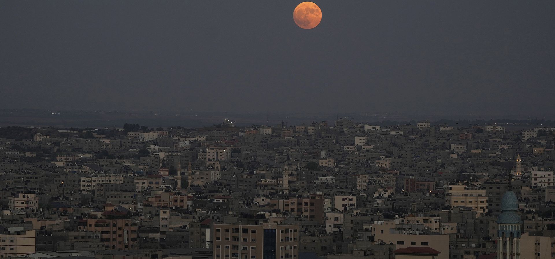 La superluna se eleva en el cielo sobre las casas de la ciudad de Gaza, el miércoles 30 de agosto de 2023. El telón cósmico se levantó el miércoles por la noche con la segunda luna llena del mes, razón por la que se considera azul. Se le llama superluna porque está más cerca de la Tierra de lo habitual y parece especialmente grande y brillante.