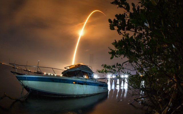 Una exposición prolongada de luz en el cielo, por el lanzamiento de un cohete, ilumina un bote abandonado cerca del Complejo de Lanzamiento 40 en la Estación de la Fuerza Espacial de Cabo Cañaveral.