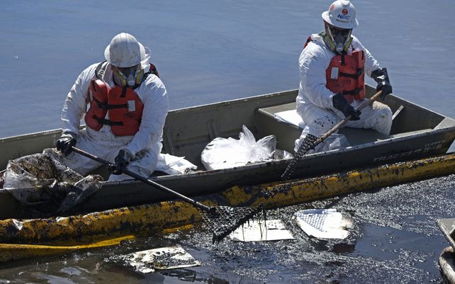 Operarios de limpieza despliegan skimmers y barreras flotantes para tratar de detener una mayor incursión de crudo en los humedales Talbert Marsh en Huntington Beach, California.