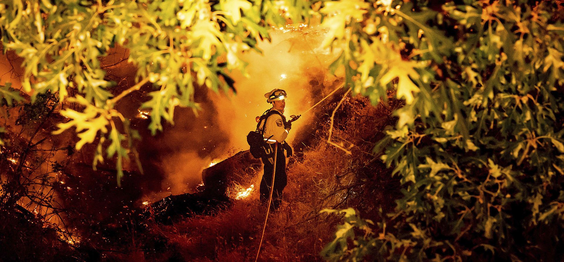 Un bombero rocía agua sobre el incendio de Electra en la comunidad de Rich Gulch del condado de Calaveras, California, el lunes 4 de julio de 2022. Según el alguacil del condado de Amador, Gary Redman, aproximadamente 100 personas se refugiaron en una instalación de Pacific Gas & Electric antes de ser evacuado por la tarde.