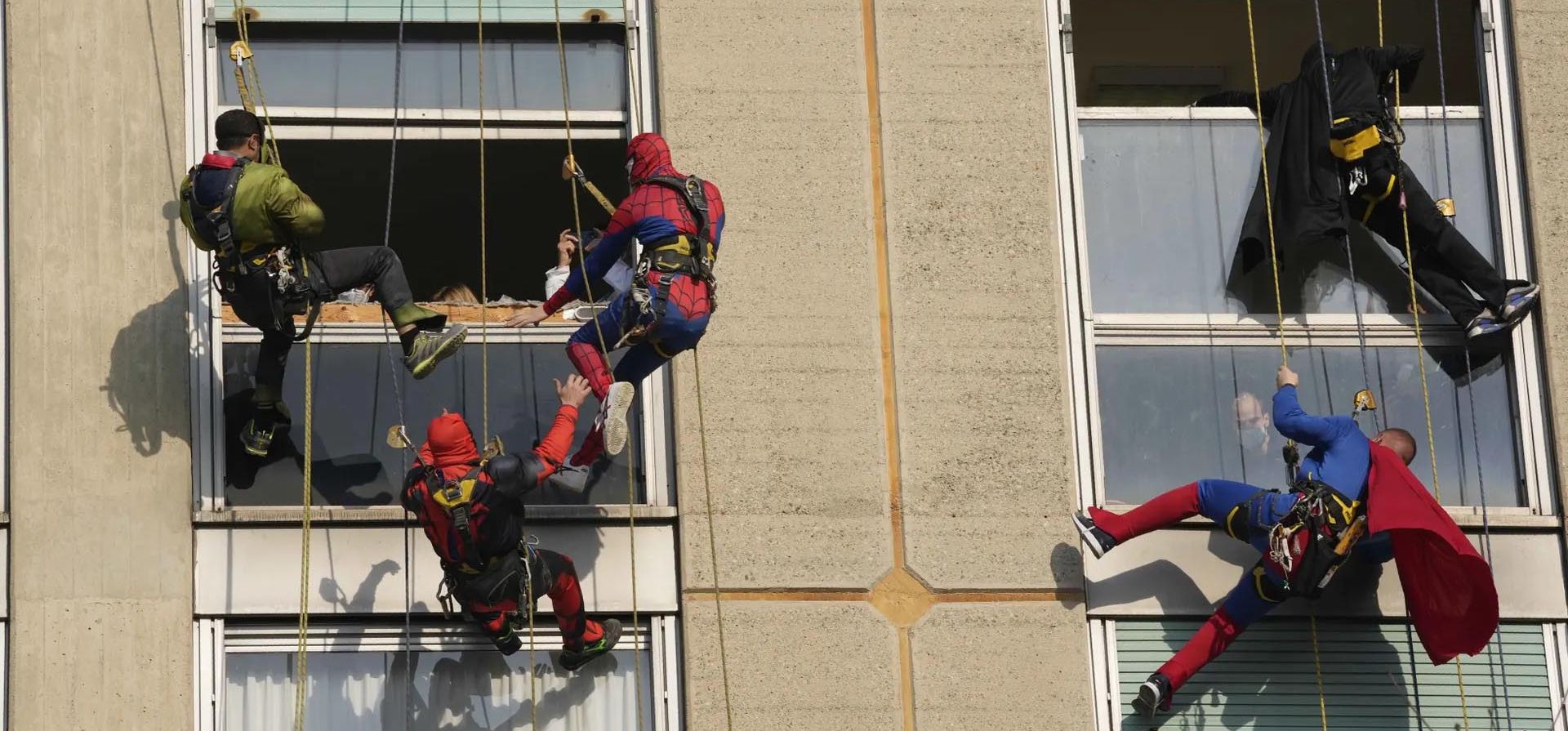 Acróbatas vestidos de superhéroes descienden en rápel por el lateral del hospital San Paolo para saludar por sorpresa a los pacientes a través de las ventanas de la unidad de pediatría. Foto: AP