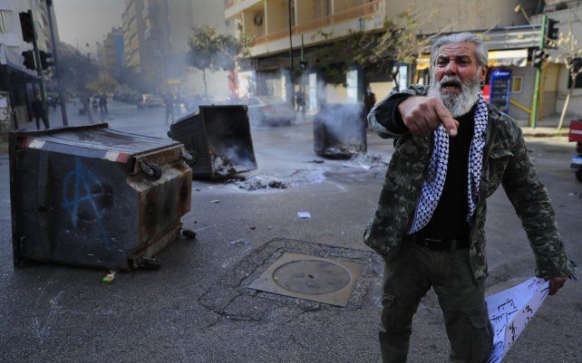Un manifestante grita consignas frente a los contenedores de basura en llamas utilizados para bloquear una carretera principal durante una protesta contra el aumento de los precios de los bienes de consumo y el desplome de la moneda local, en Beirut, Líbano.