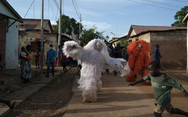 Un niño huye de hombres vestidos como Kankurang durante una procesión ritual en Bakau