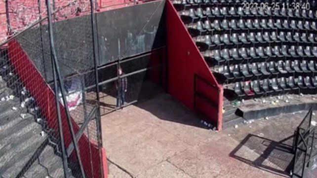Astore parado contra la puerta de alambrado mientras por detrás se llevan la bandera.