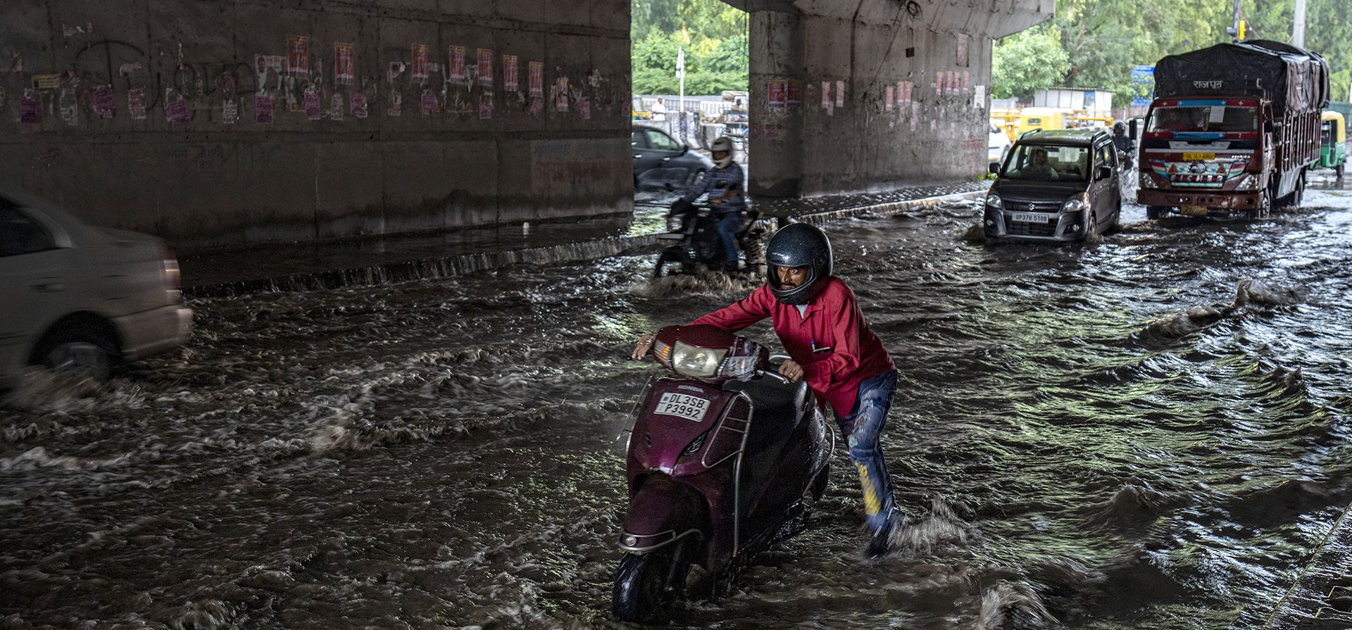 Un hombre empuja su scooter por una carretera inundada después de las lluvias que azotan Nueva Delhi, India, el jueves 22 de septiembre de 2022.