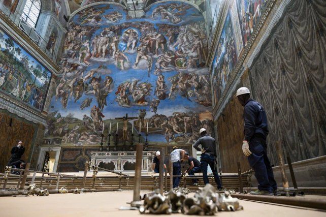 Trabajadores del Vaticano frente a los frescos del Juicio Final pintados por Miguel Ángel Buonarroti en la Capilla Sixtina.