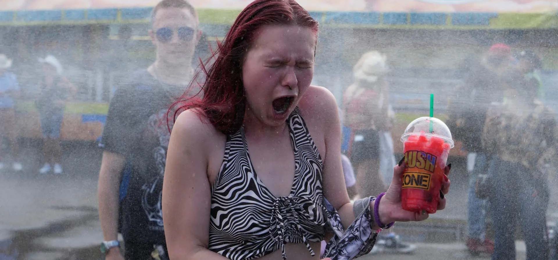 Una mujer reacciona al agua fría en una estación de enfriamiento durante un período de clima caluroso en medio de la estampida de Calgary en Alberta, Calgary, Canadá. Fotografía: Todd Korol/Reuters Una mujer reacciona al agua fría en una estación de enfriamiento durante un período de clima caluroso en medio de la estampida de Calgary en Alberta, Calgary, Canadá. Fotografía: Todd Korol/Reuters