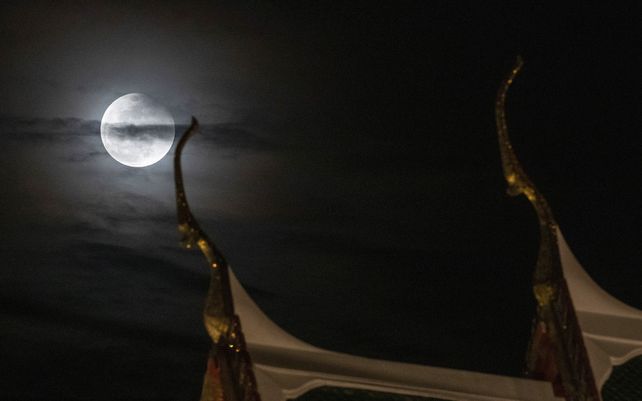 Una vista de la luna observada detrás del templo Suthat en Bangkok