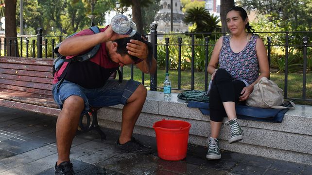 Un hombre se refresca la cabeza con agua fría mientras su pareja espera su turno.
