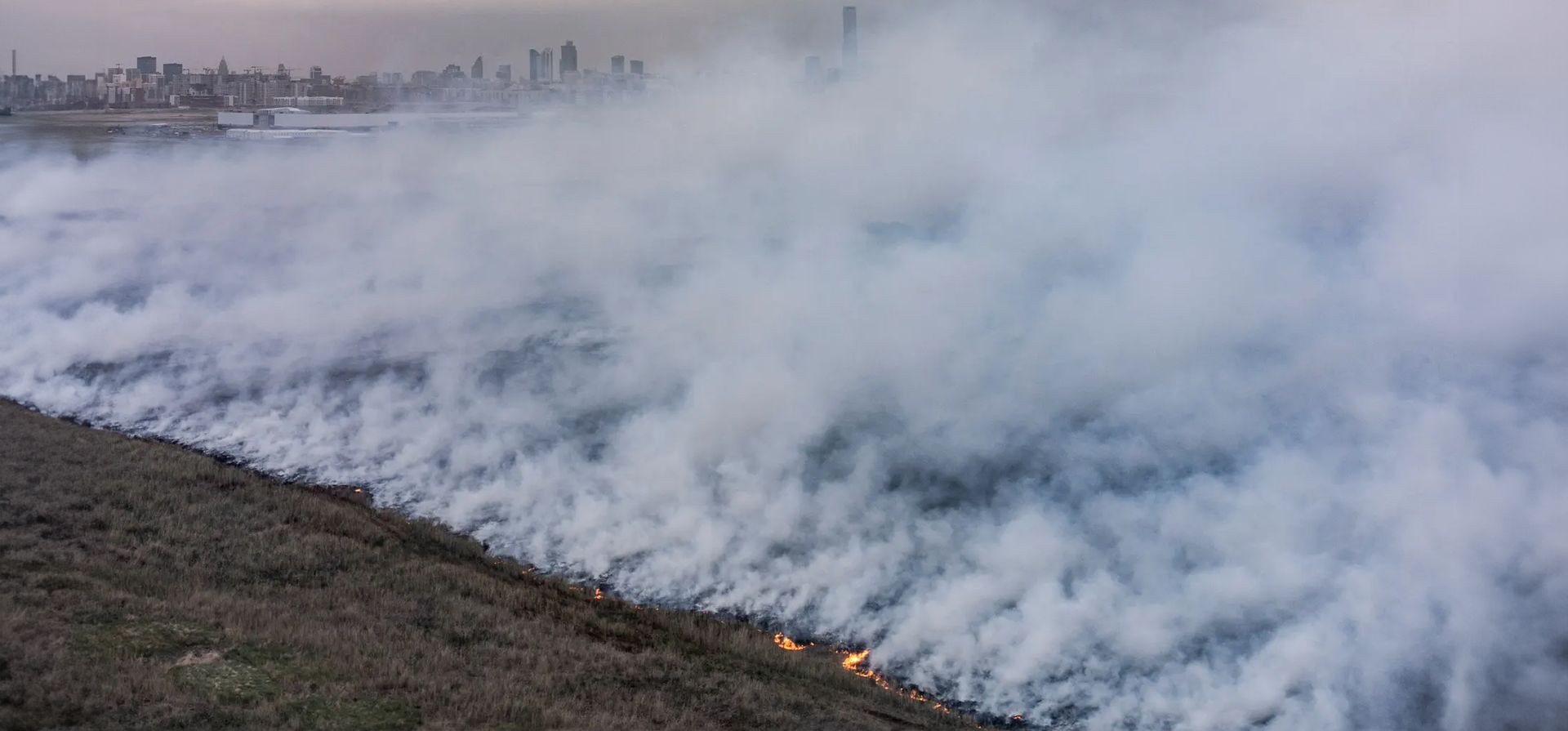Astana, Kazajstán. El humo de un incendio forestal se eleva sobre una estepa contra el telón de fondo de la capital. Fotografía: Turar Kazangapov/Reuters Astana, Kazajstán. El humo de un incendio forestal se eleva sobre una estepa contra el telón de fondo de la capital. Fotografía: Turar Kazangapov/Reuters