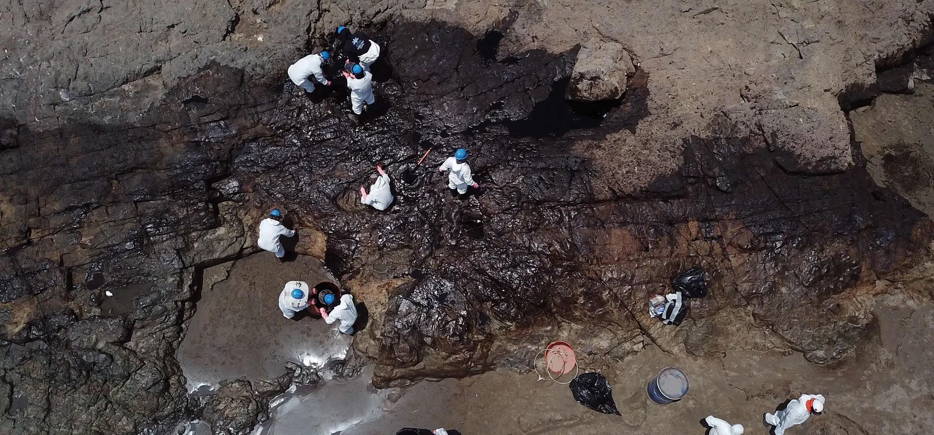 Equipos de limpieza retiran petróleo de una playa en la provincia peruana del Callao, luego de un derrame de un camión cisterna en la refinería La Pampilla causado por el oleaje anormal. Fotografía: Cris Bouroncle/AFP/Getty Images