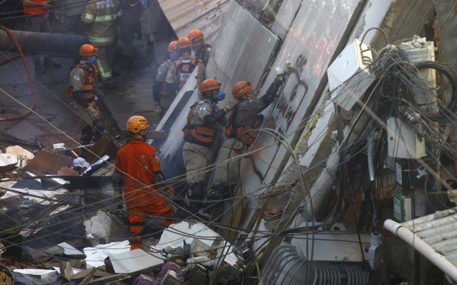 Los bomberos usan un perro rastreador para buscar posibles sobrevivientes en un edificio de cuatro pisos que se derrumbó durante la noche en el barrio humilde de Rio das Pedras en Río de Janeiro, Brasil.