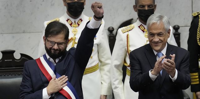 El nuevo presidente de Chile, Gabriel Boric, a la izquierda, levanta el puño mientras el presidente saliente, Sebastián Piñera, aplaude durante la ceremonia de juramentación de Boric en el Congreso en Valparaíso, Chile, el viernes 11 de marzo de 2022. (Foto AP/Esteban Felix)