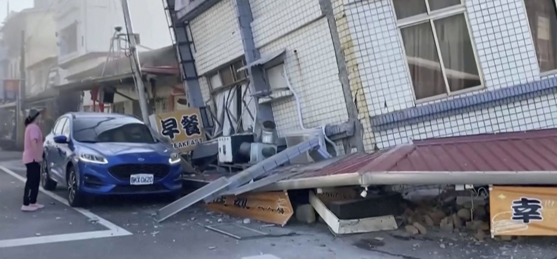 Imagen de video publicado por TVBS, una mujer se encuentra cerca de un edificio parcialmente derrumbado en Hualien, al este de Taiwán, el miércoles 3 de abril de 2024. Un poderoso terremoto sacudió toda la isla de Taiwán la madrugada del miércoles, derrumbando edificios en una ciudad. y creando un tsunami que arrasó las costas de las islas japonesas. (TVBS vía AP) Imagen de video publicado por TVBS, una mujer se encuentra cerca de un edificio parcialmente derrumbado en Hualien, al este de Taiwán, el miércoles 3 de abril de 2024. Un poderoso terremoto sacudió toda la isla de Taiwán la madrugada del miércoles, derrumbando edificios en una ciudad. y creando un tsunami que arrasó las costas de las islas japonesas. (TVBS vía AP)