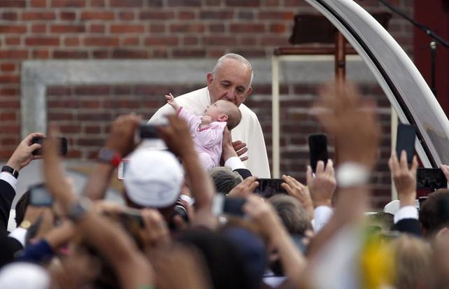 El papa Francisco besa a un bebé desde el papamóvil antes de dirigirse a dar una misa en Filadelfia. (Foto: AP)