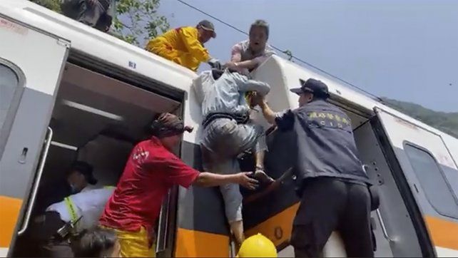Los socorristas ayudan a una de las víctimas a salir del tres tras el violento impacto.