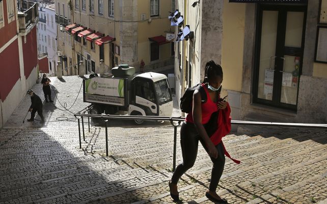 Una mujer de color pasa junto a los trabajadores que lavan la calle en el centro antiguo de Lisboa. Un alto funcionario europeo de derechos humanos está dando la voz de alarma sobre un aumento del racismo y la discriminación en Portugal.