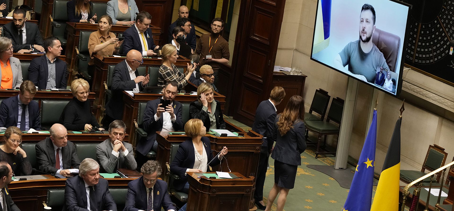 El primer ministro de Bélgica, Alexander De Croo, a la derecha, baja del podio mientras el presidente de Ucrania, Volodymyr Zelenskyy, observa desde la pantalla, a la derecha, durante una sesión en la cámara plenaria del Parlamento Federal belga en Bruselas, Bélgica, el jueves 31 de marzo de 2022.